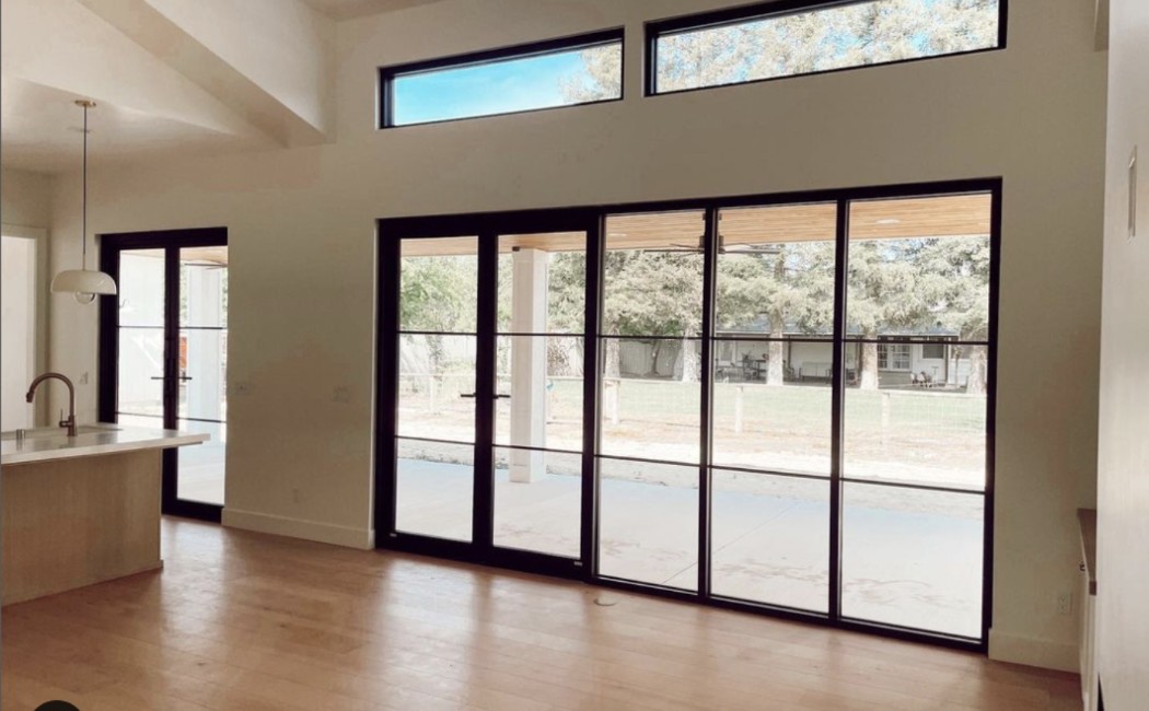 Modern large patio door installation featuring expansive black-framed sliding glass doors that open to a spacious outdoor patio.