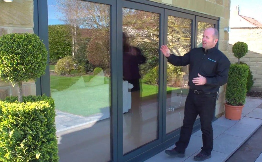Professional demonstrating patio door installation with modern aluminum-framed sliding glass doors at a residential home entrance.