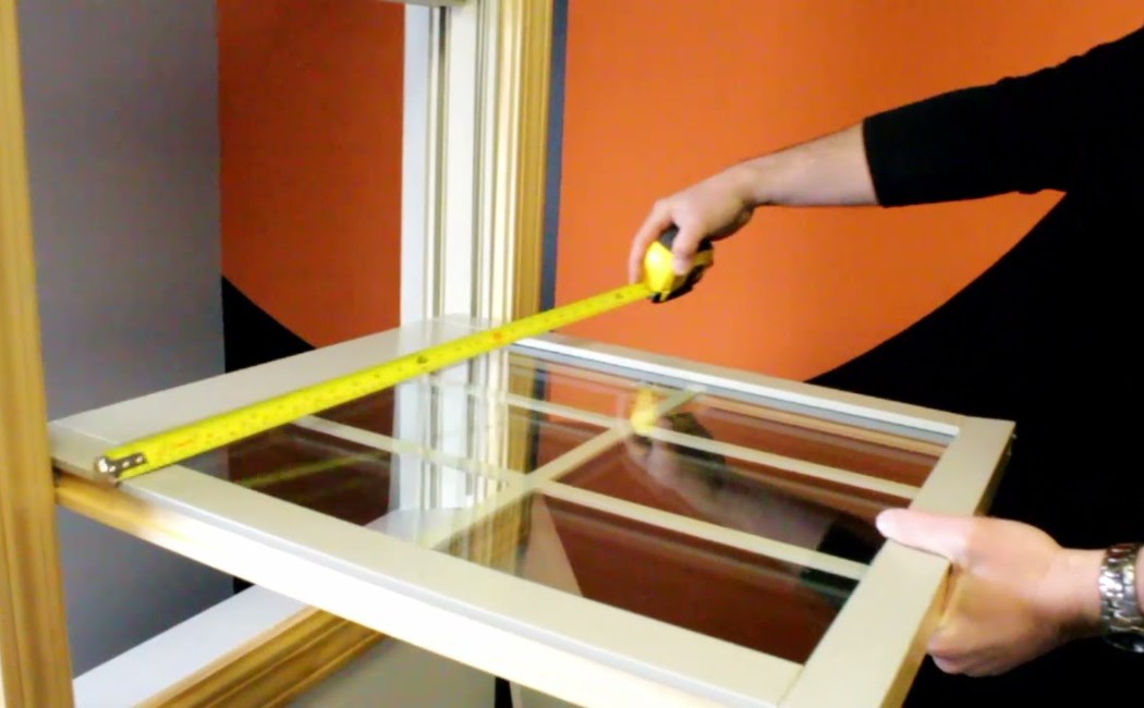 Window installation expert measuring a replacement window to ensure an accurate fit before installation.