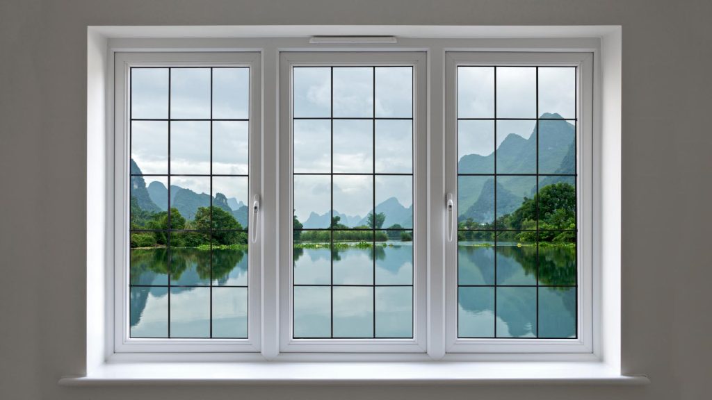 Pane Windows featuring elegant white frames overlooking a serene lake and dramatic green mountains, bringing natural beauty and timeless style into the space.